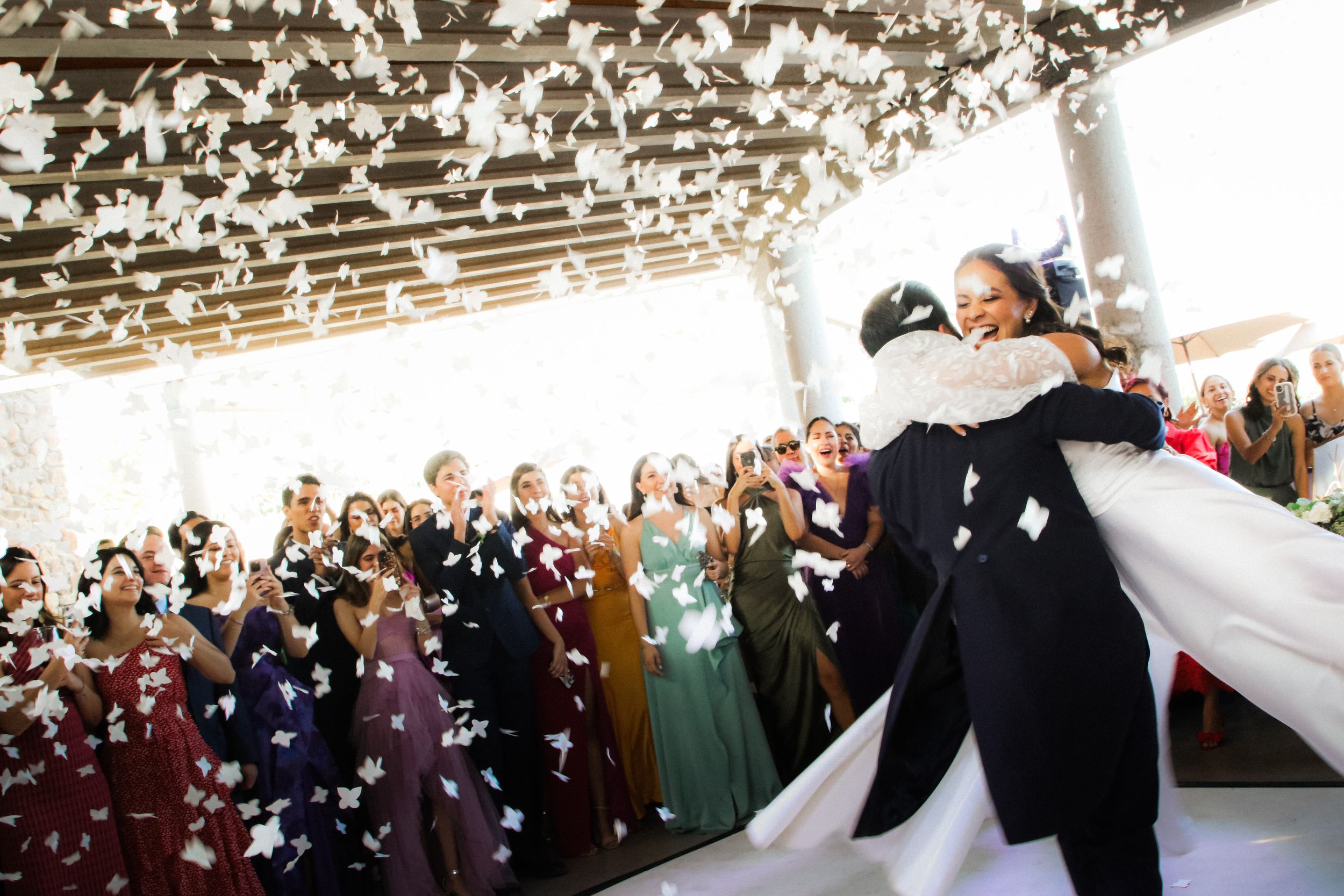 Newlyweds share first dance under twinkling lights with guests watching.