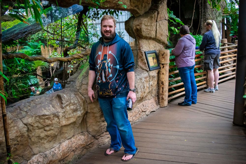 Visitors exploring a rocky pathway in a tropical zoo or garden setting.