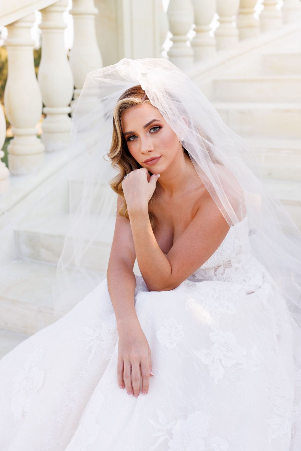Ethereal bridal portrait series featuring flowing white veil and lace wedding gown against classic white balustrades.