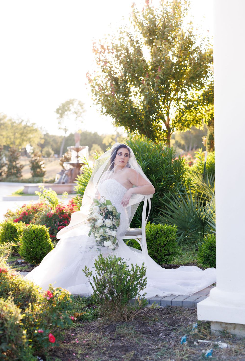 Garden bridal session featuring flowing white gown and bouquet amid landscaped grounds at sunset.