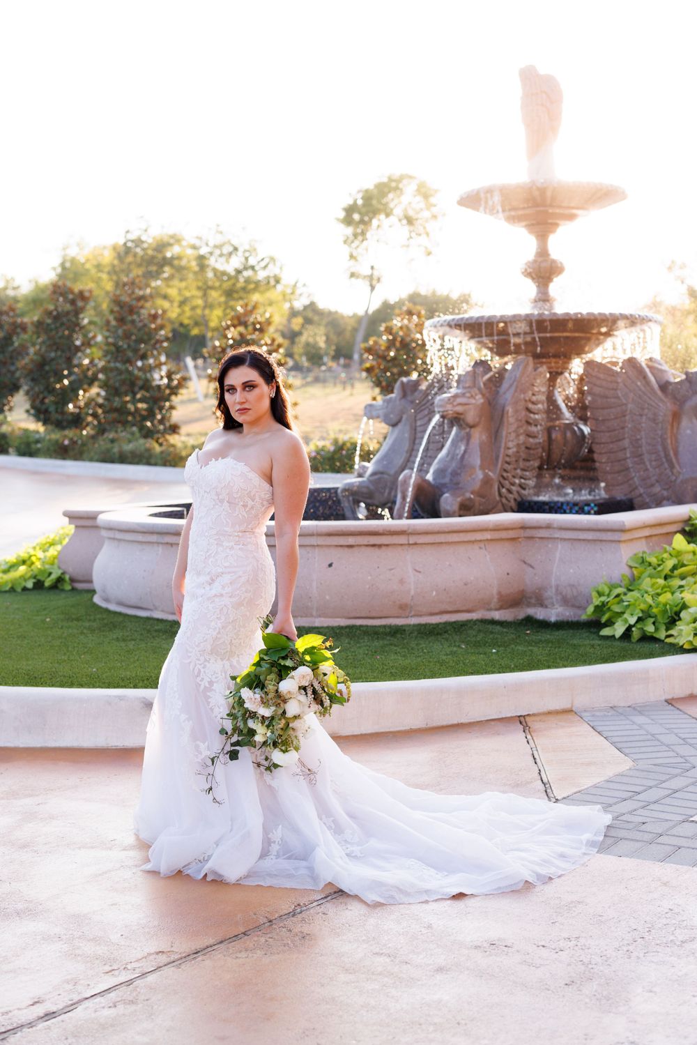 A stunning bridal portrait session featuring a white wedding gown against an elegant fountain backdrop at sunset.