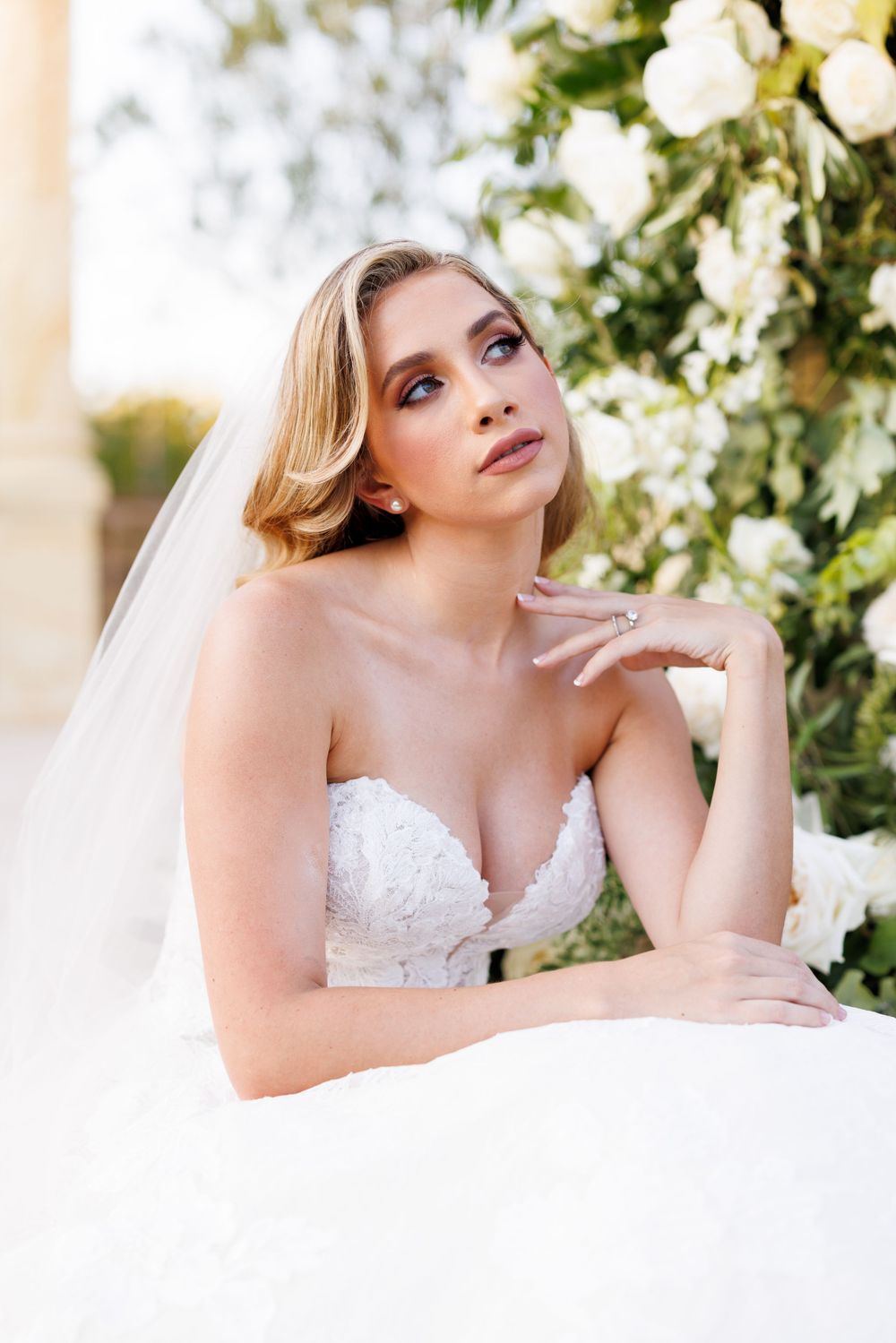 Elegant bridal portraits captured against a backdrop of white roses and greenery.