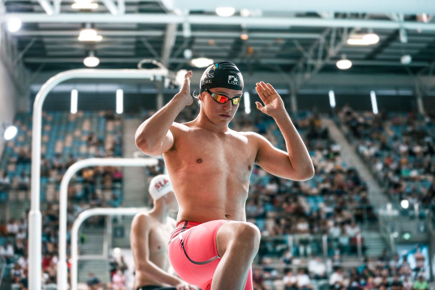 Athlete celebrating in swimming pool stadium with energetic pose.