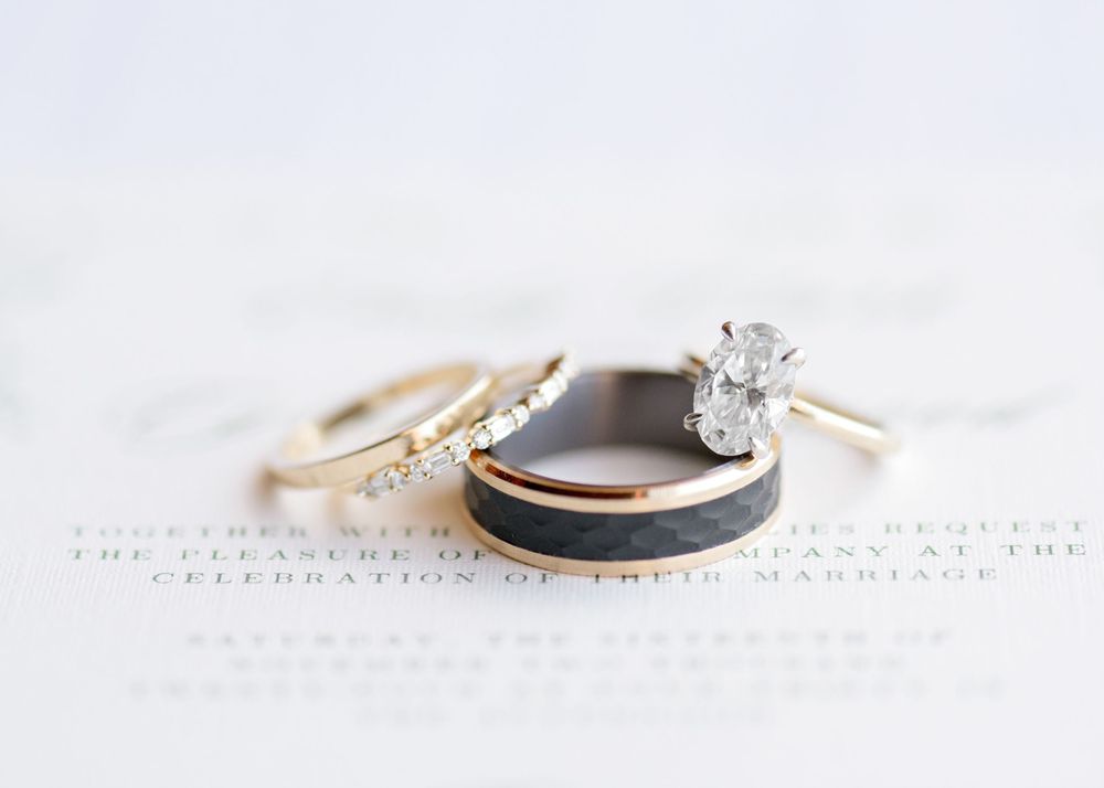 Close-up view of elegant engagement rings and wedding bands arranged on white textured paper in natural light.