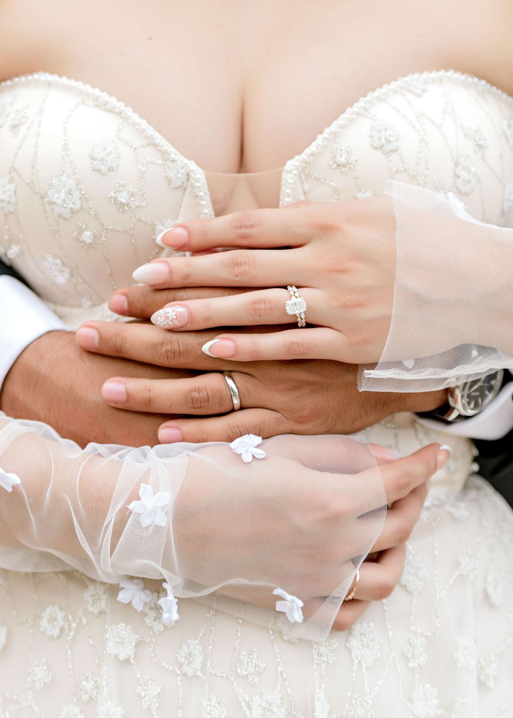 Close-up sequence showing bride and groom's hands with wedding rings against white lace dress.