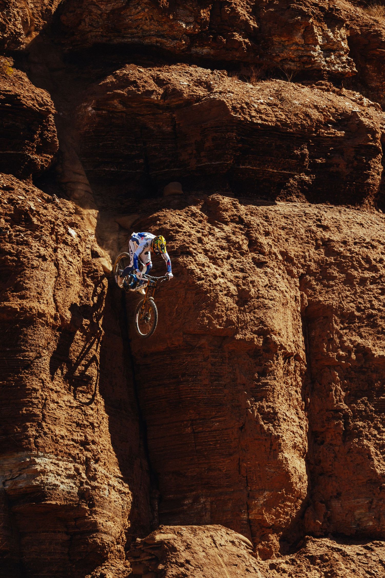 Brendan Fairclough performing extreme jump off steep red rock cliff face.
