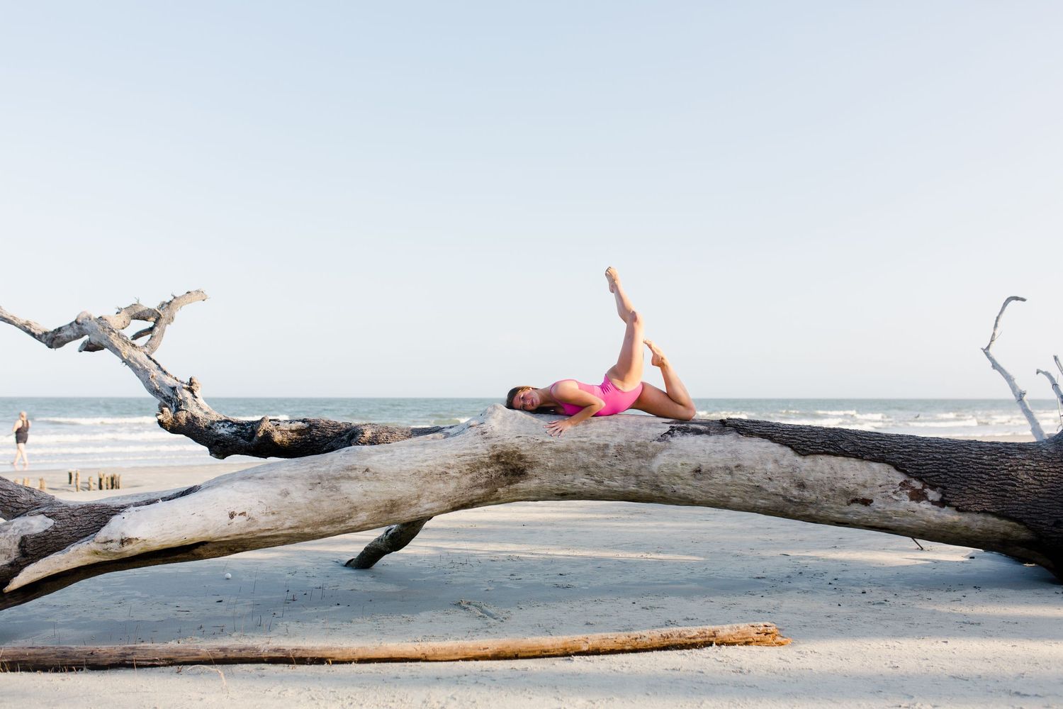 Dancer on a dead tree against a cloudy sky on sandy terrain in Hunting Island for Beaufort dance photography.