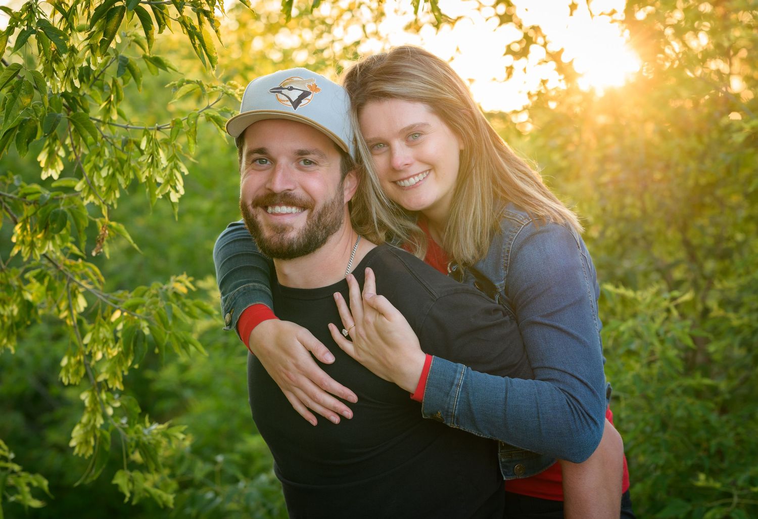 Happy couple embracing outdoors with golden sunlight filtering through trees.