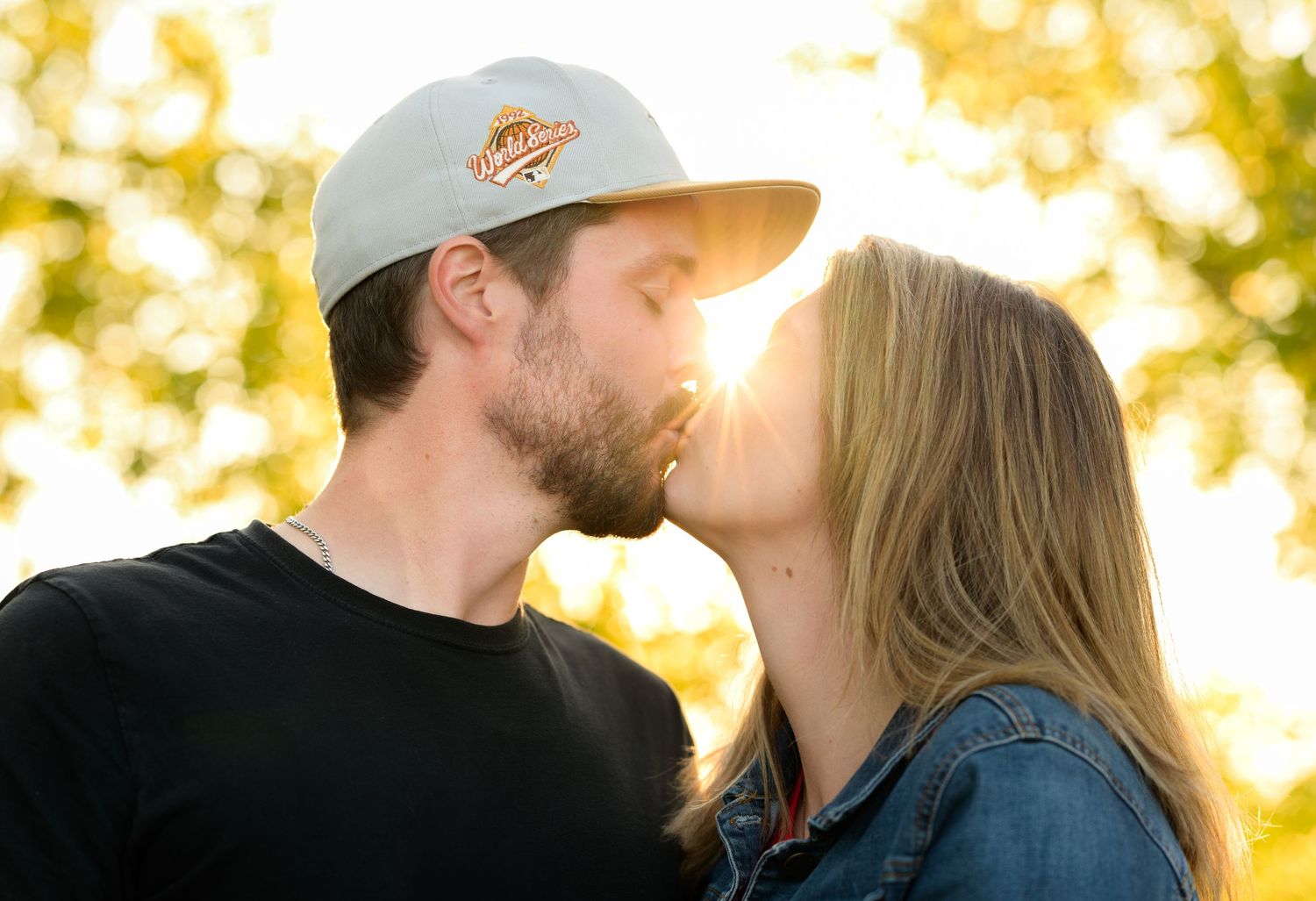 Romantic couple sharing an intimate moment at sunset with golden bokeh background.