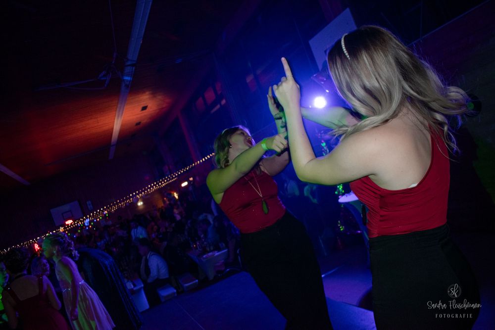 A nightclub scene with blue lighting and silhouettes of people dancing and performing on stage during a live event.