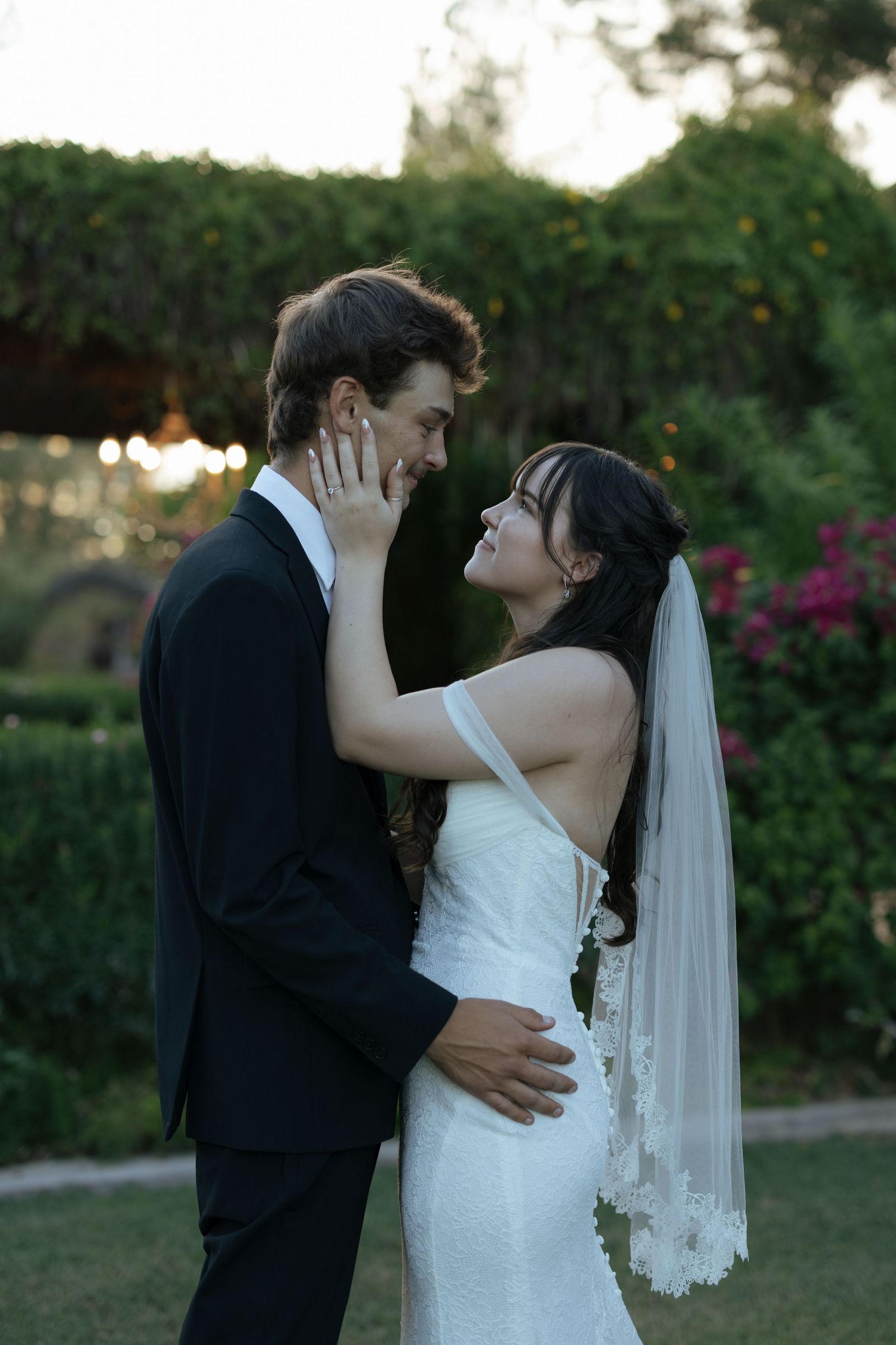 A western-style wedding couple in black and white attire sharing a tender moment with a rustic floral bouquet.