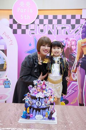 Woman and young girl pose with decorated birthday cake at Paris 5th birthday party with purple and pink theme.