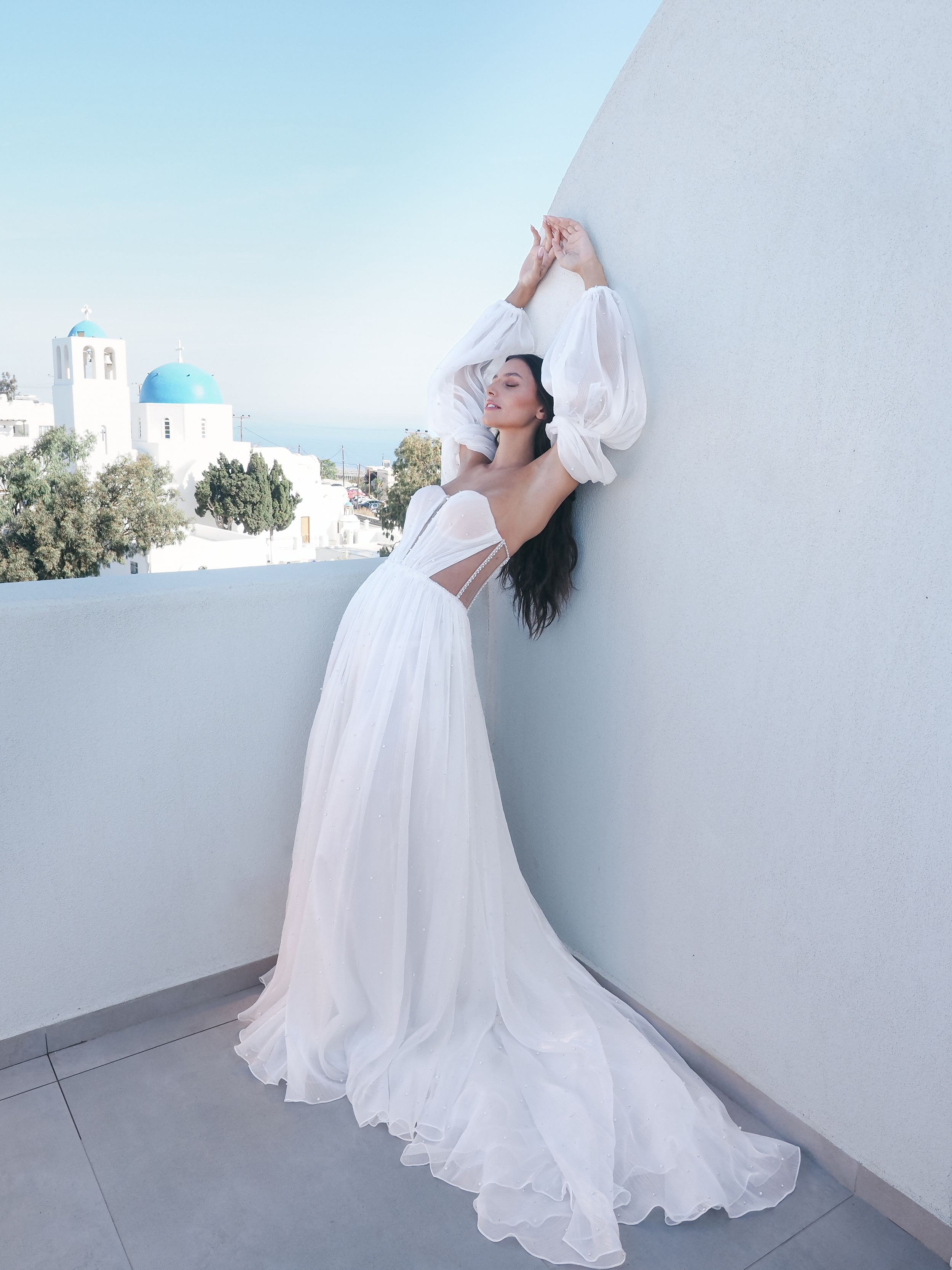 White wedding dress photoshoot with Santorini's blue domed church in background.