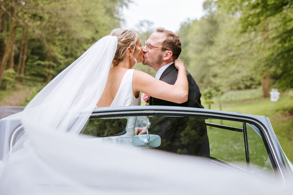 Bride and groom kissing whilst the veil is being pulled by the wind, captured by Sylvia Patchell Photography.