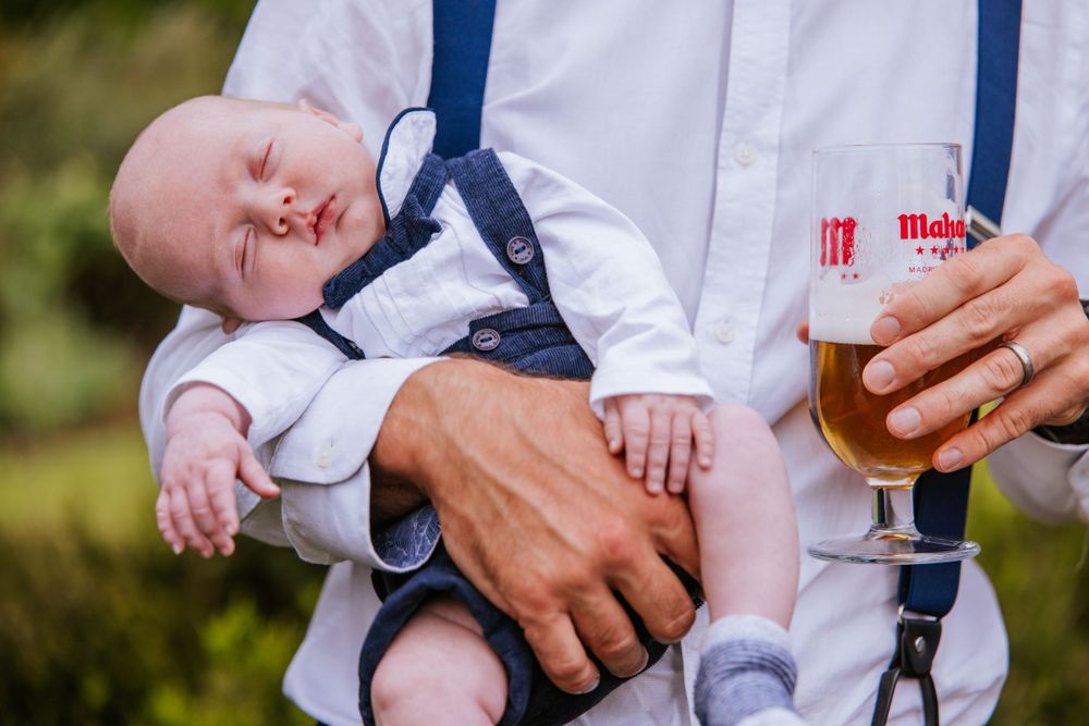 Baby asleep during group photos at Harper Weddings venue, Cain Manor in Hampshire.