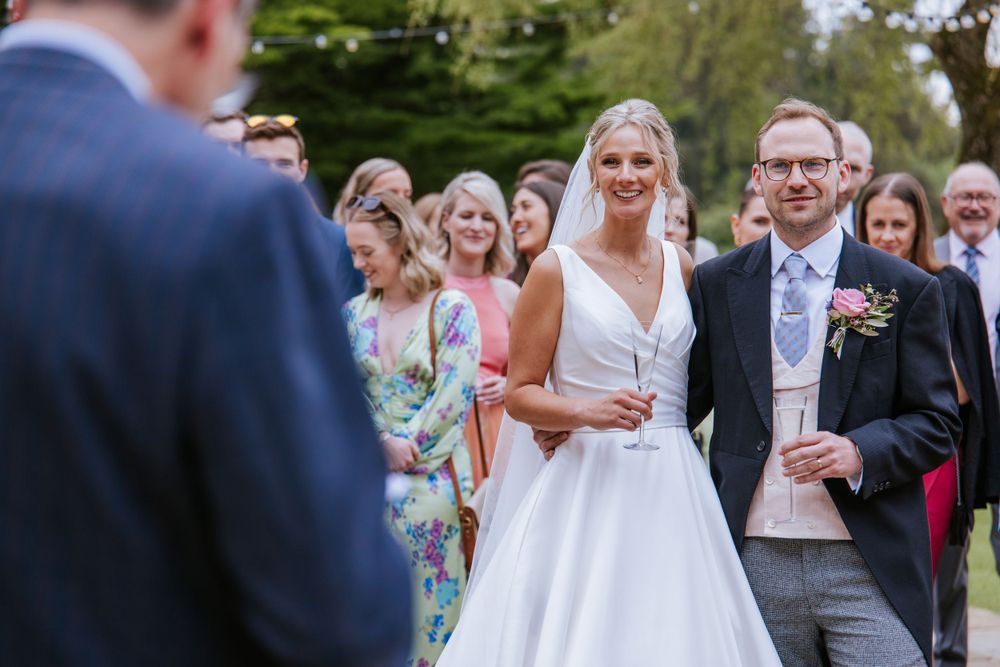 Bride and groom listening to father's of the bride speech in Harper weddings Cain Manor in Hampshire.