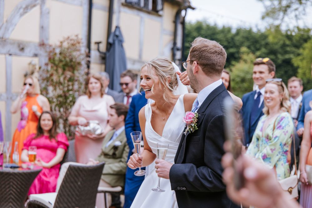 Bride and groom laughing during father's of the bride speech in Harper Weddings Cain Manor, Hampshire.