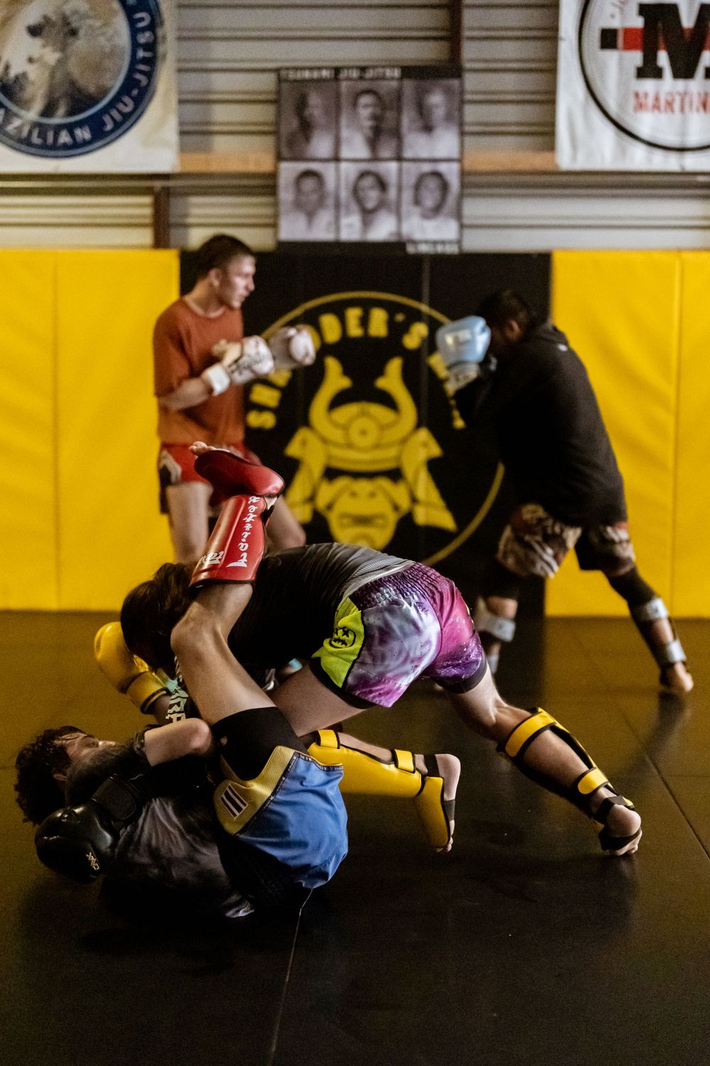 Martial arts practitioners grappling on mat during intense training session.