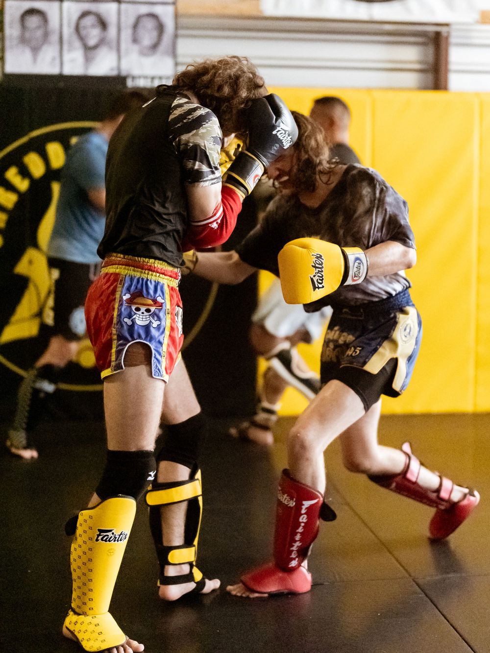 Kickboxers in protective gear practicing combat moves during training session.