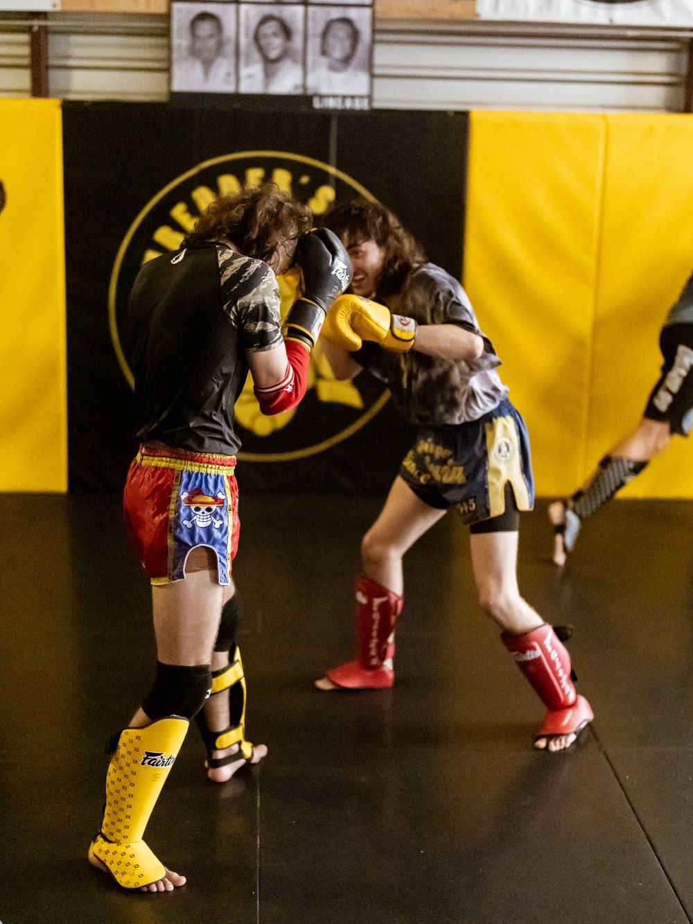 Two fighters exchange punches during sparring session at martial arts training facility.