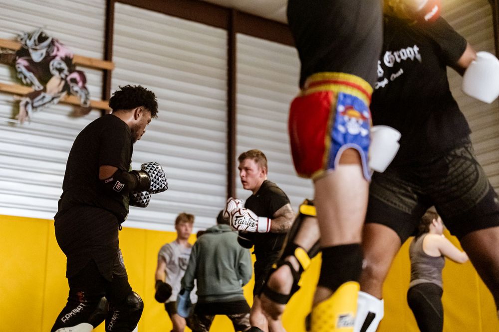 Dynamic martial arts training session with multiple participants in a gym setting.