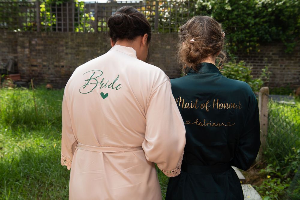 Two robed figures stand in a garden wearing matching light and dark bathrobes with embroidered text.
