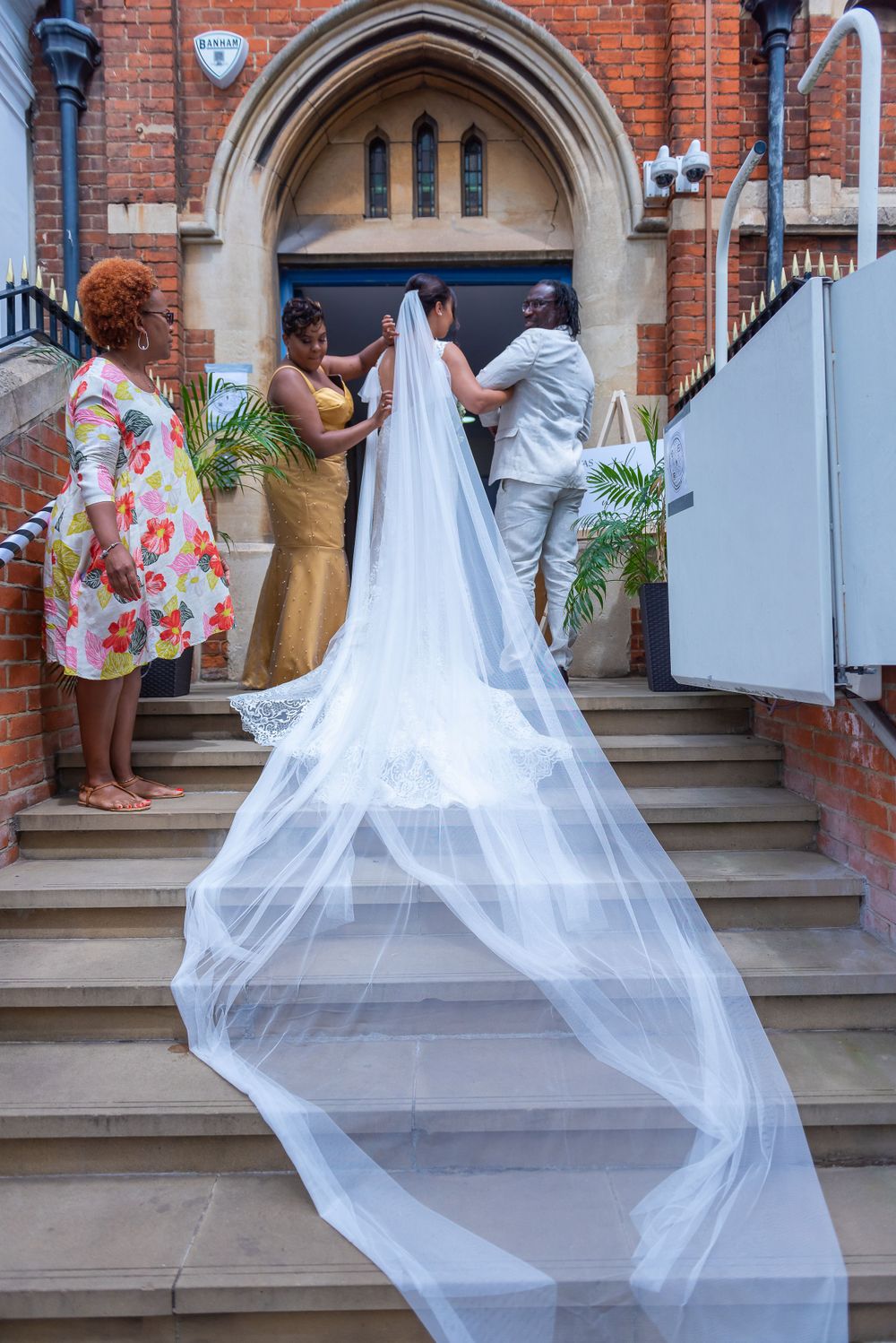 A flowing white veil trails down church steps during a wedding ceremony entrance.