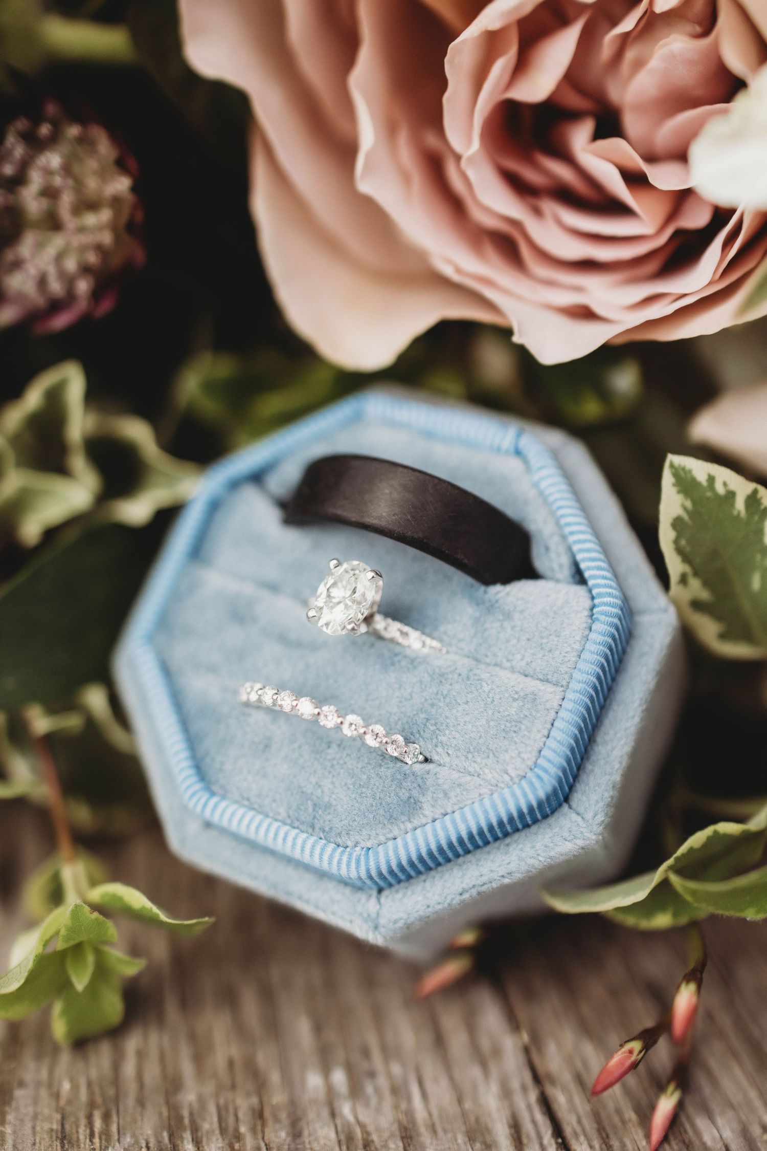 A sparkling diamond engagement ring nestled in a light blue velvet ring box with pink roses.