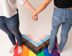 Rainbow colored stripes on floor with people's feet standing on them.