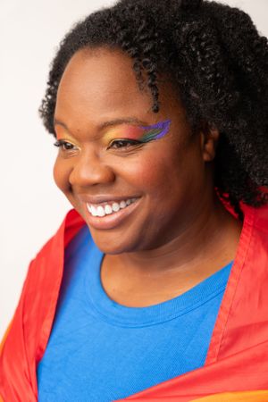 Person wearing bright blue shirt and rainbow makeup with joyful expression.
