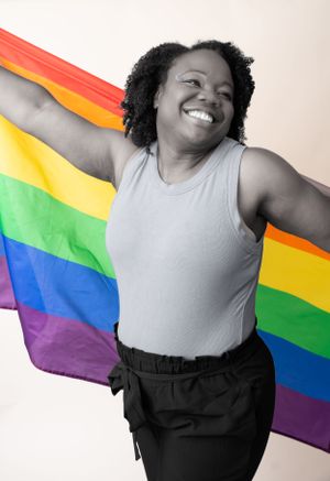 Black and white photo with pride flag being held up in celebration pose.