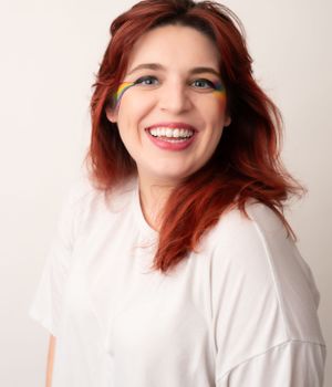 Studio portrait featuring yellow pride flag inspired eye makeup and bright smile.