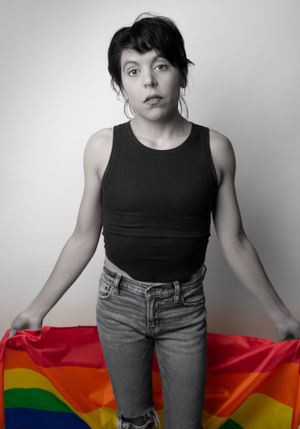A fashion portrait series with someone posing with a rainbow pride flag.