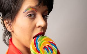 Playful moments with a rainbow lollipop against a gray background.