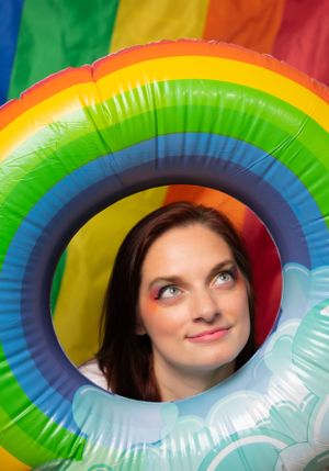 Playful peeks through a rainbow-colored inflatable ring against white background.