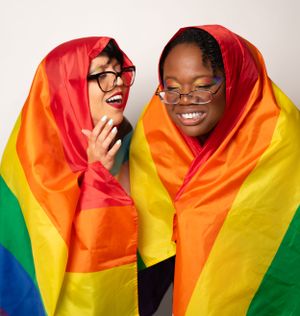 Candid moments of laughter while wrapped in vibrant pride flag colors.
