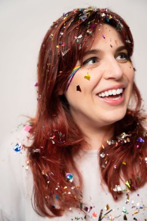 Joyful portrait with multicolored confetti sparkling against white background.