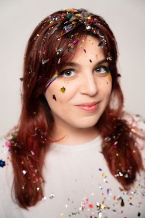 Playful studio portrait with sparkling confetti and warm lighting.