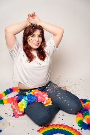 Studio photo with rainbow colored decorations and glitter against a white background.