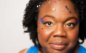 Close-up portrait with sparkly confetti and bright blue outfit against white background.