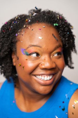 Expressive studio portrait with colorful makeup and glitter details.