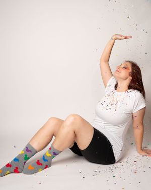 Person in white shirt lying on floor with confetti scattered around in artistic photo series.