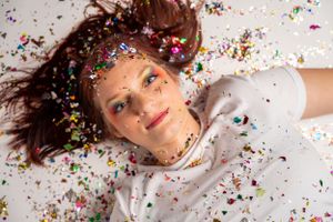 Colorful confetti scattered around with rainbow decorations in a creative portrait photography setup.