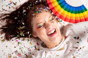 Artistic portrait with rainbow pride fan and scattered confetti creating a festive atmosphere.