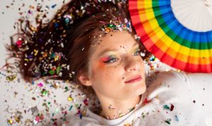 Playful studio portrait featuring rainbow colors and sprinkled confetti decorations.