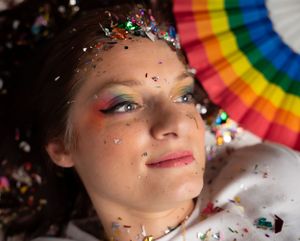 Creative photography with rainbow fan and sparkly confetti elements on white backdrop.