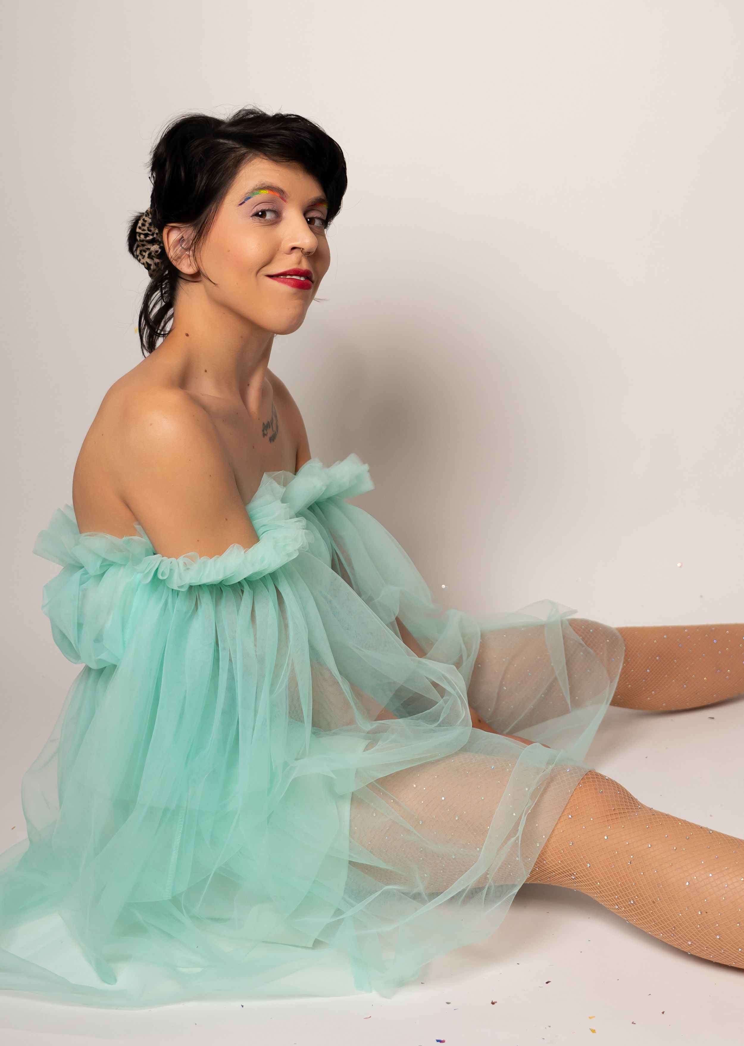 Elegant pose in mint green tulle dress against simple studio background.