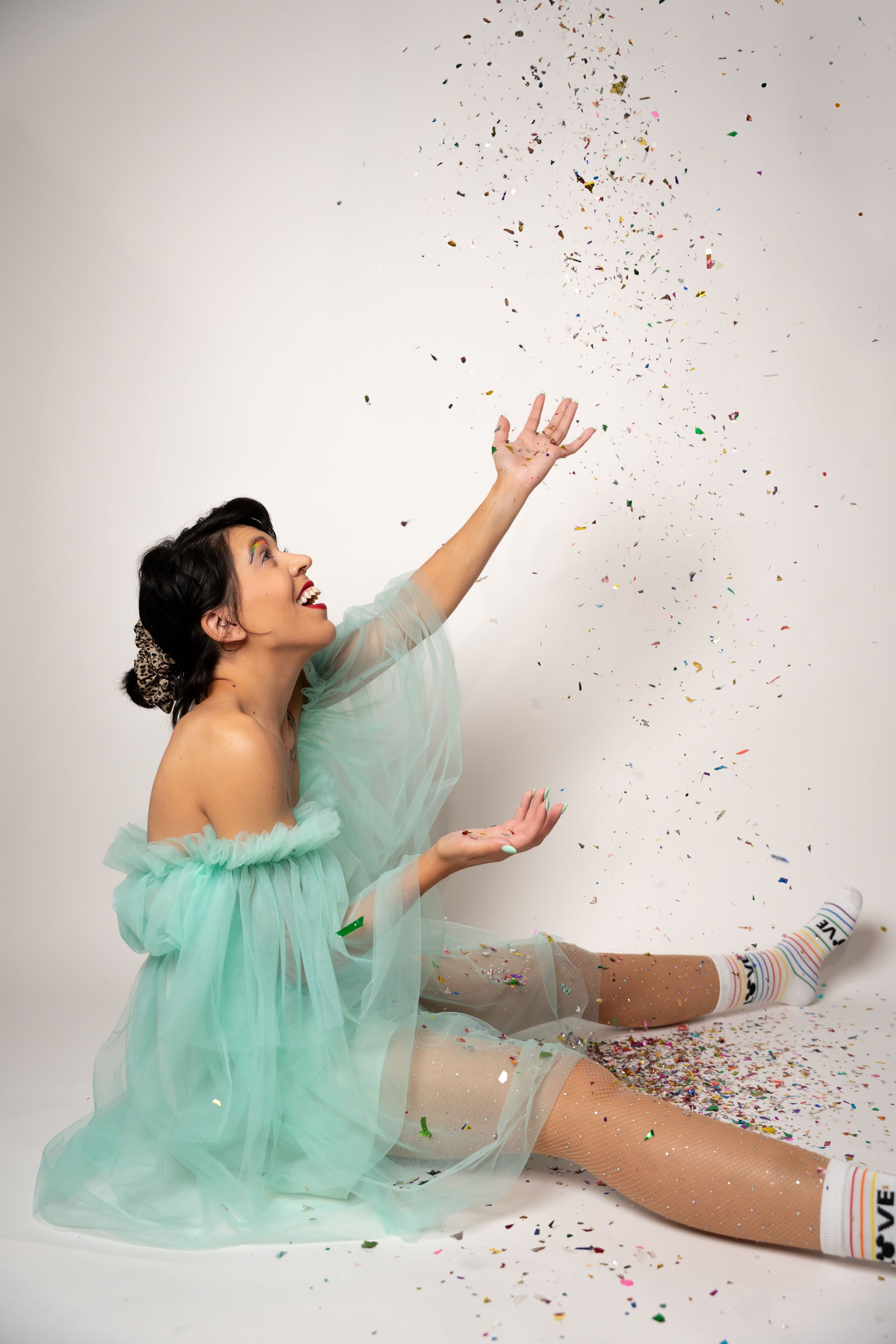 Playful photos on floor with mint green dress and falling confetti.