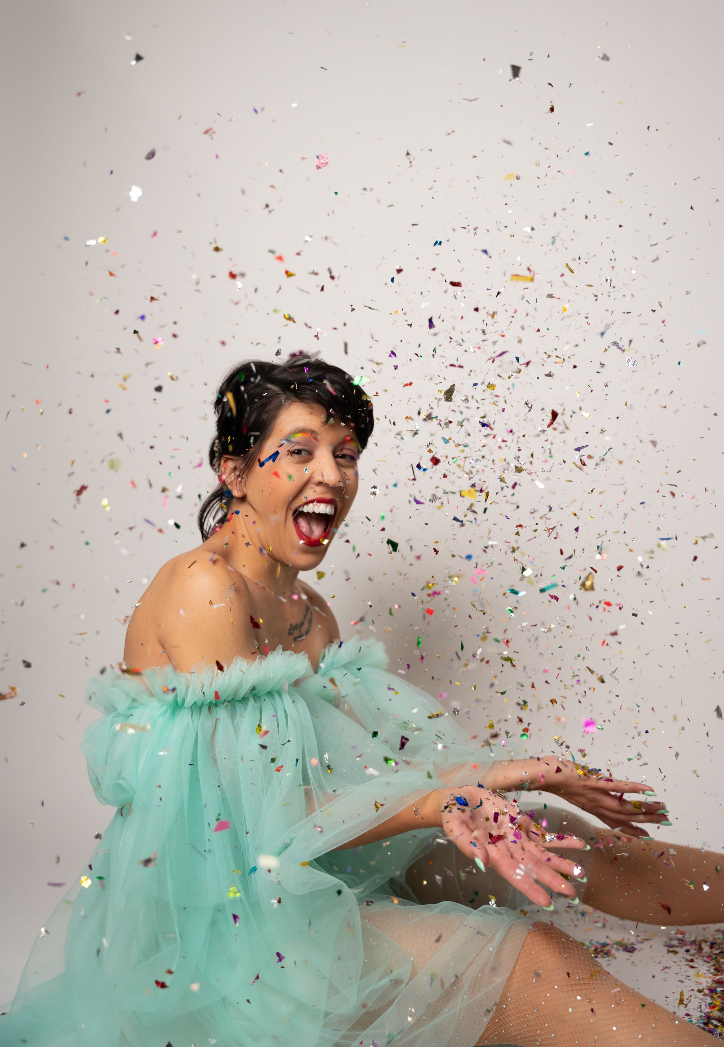 Someone in a mint green tulle dress playfully tosses colorful confetti in a dynamic photo sequence.