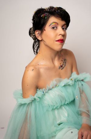 Figure in a mint green ruffled dress poses gracefully against a white studio background.